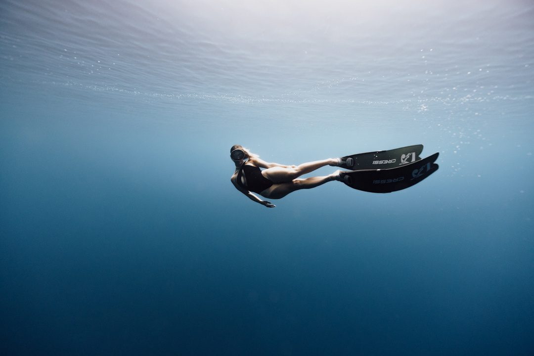 Freediver with long fins in deep blue water